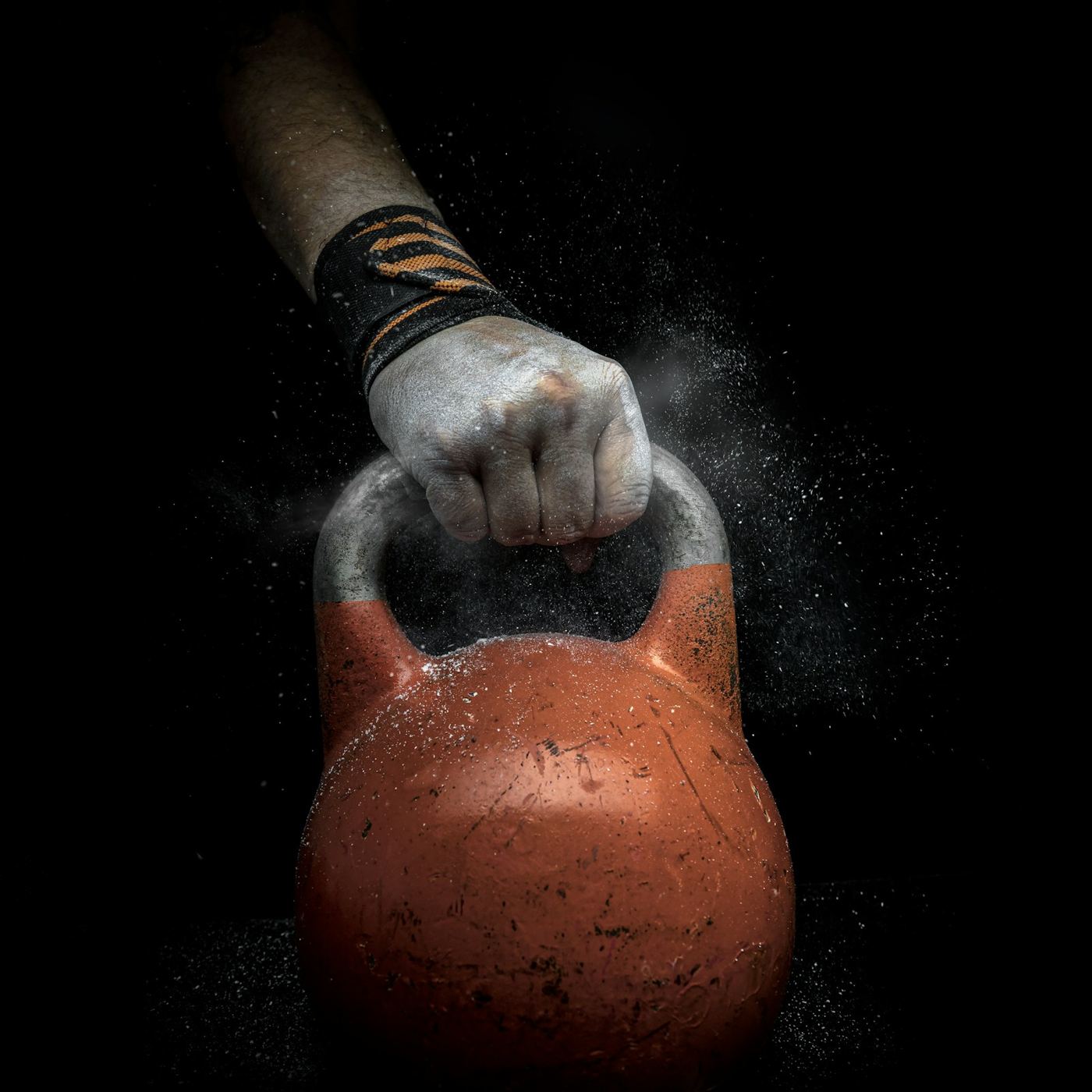 Hånd med kritt som griper en oransje kettlebell
