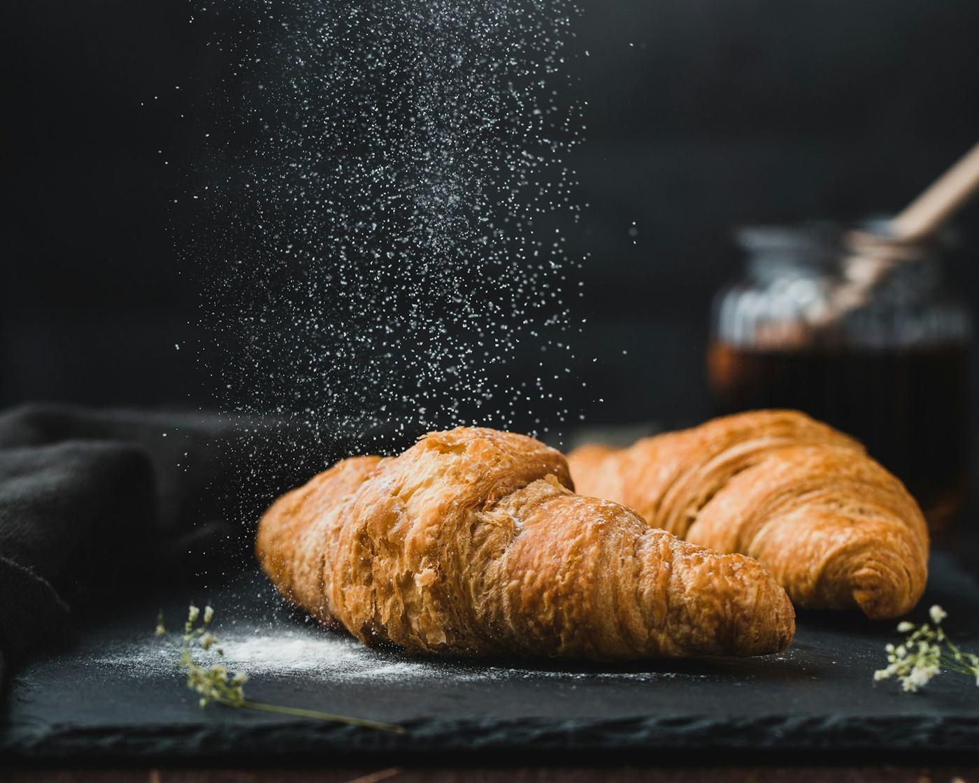 To croissanter på skiferplate med mel som drysser ned